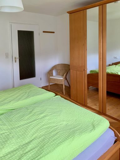 Schlafzimmer Schlafzimmer mit zwei grünen Bettdecken, Kleiderschrank und einem Stuhl.