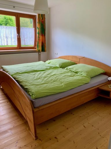 Schlafzimmer Doppelbett mit grüner Bettwäsche in einem hellen Schlafzimmer. Holzfußboden.